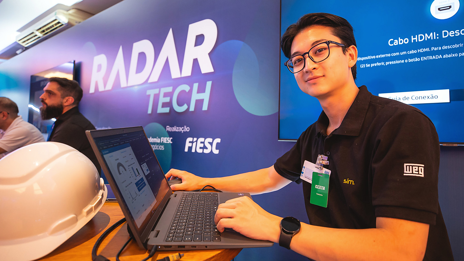 Participante com identificação WEG opera computador no espaço de demonstrações do Radar Tech