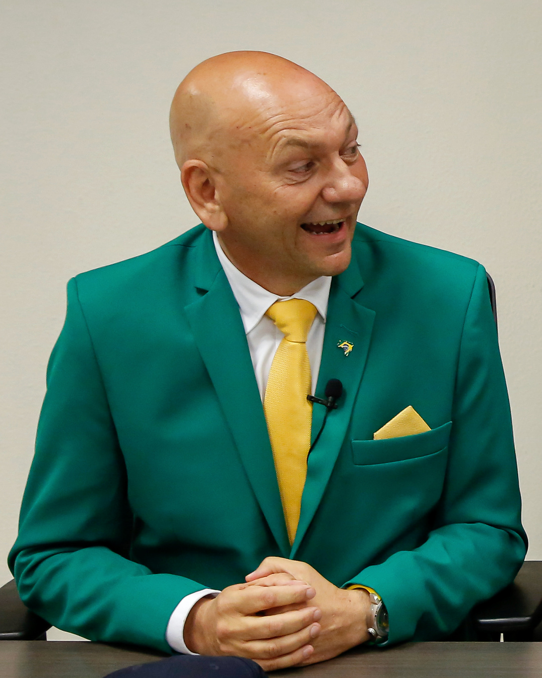 Luciano Hang de terno verde e gravata amarela durante transmissão ao vivo em Florianópolis